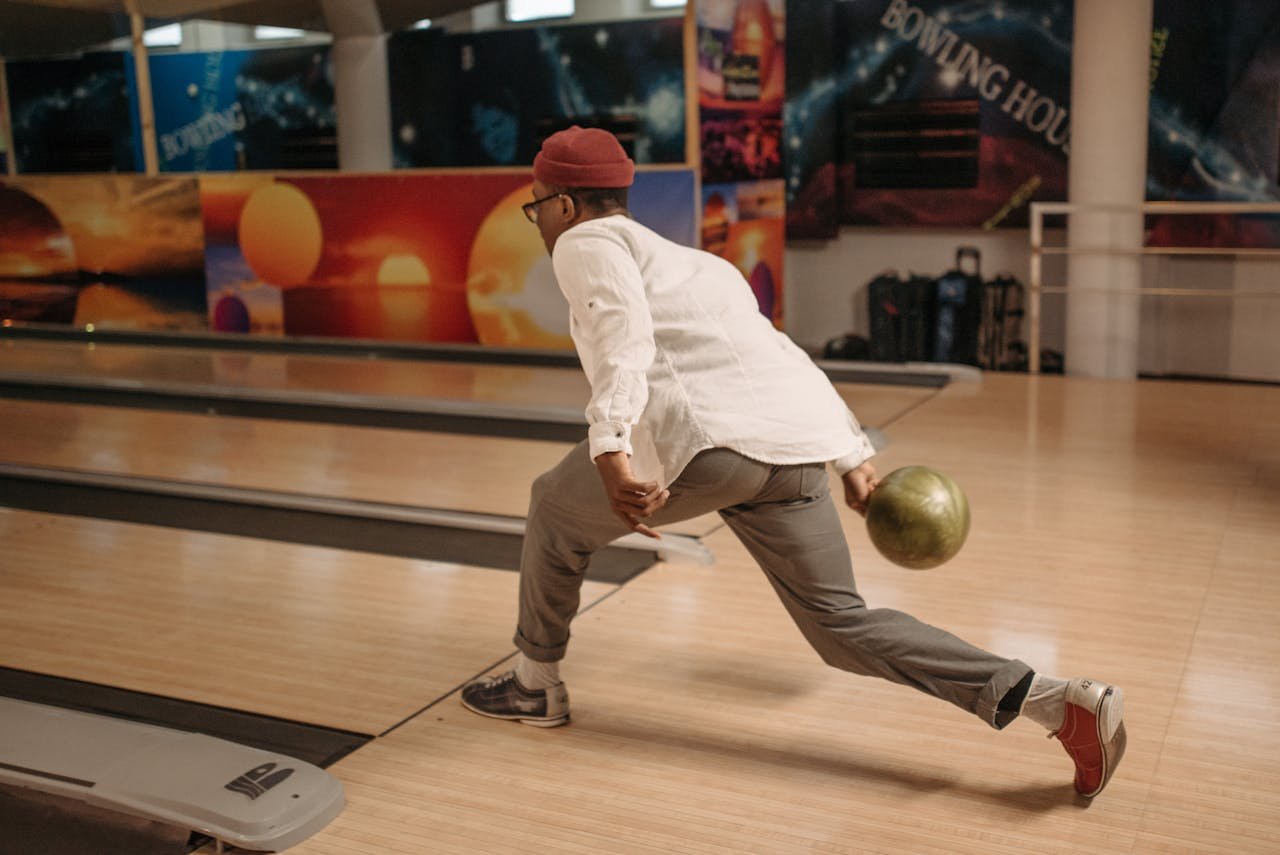 Focused man releasing a bowling ball at a modern indoor bowling alley.