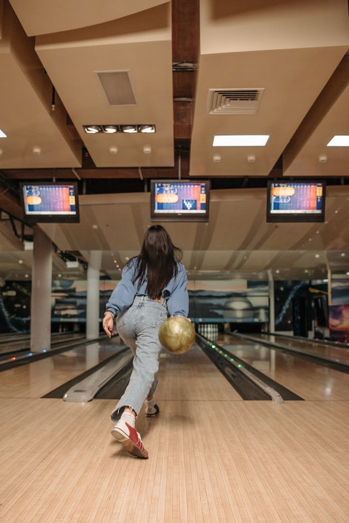 A woman engages in a lively bowling game at an indoor alley, showcasing focus and style.